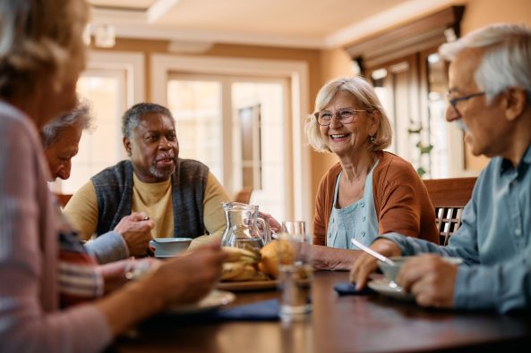 Happy senior woman talking to her friends during a lunch in residential care home.
